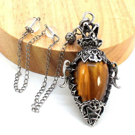 Decorative pendant with tiger's eye stone and silver chain on a wooden block