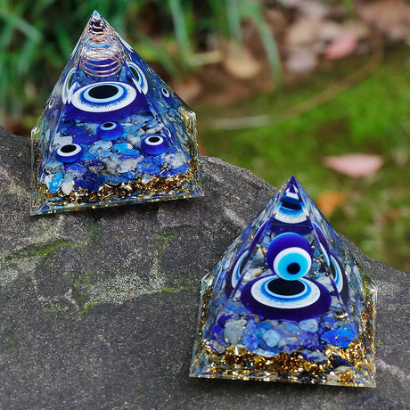Two pyramid-shaped decorative items with blue and gold colors on a stone surface.