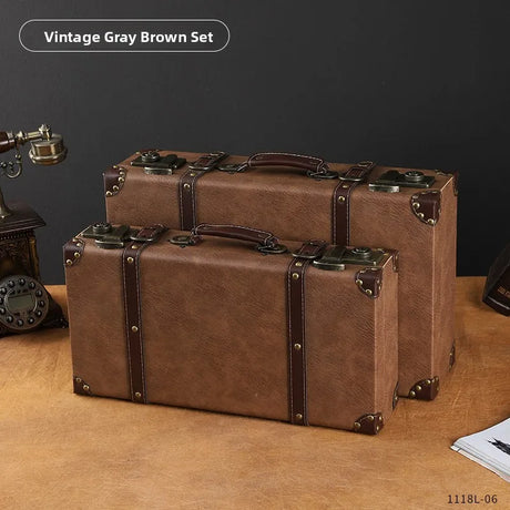 Two vintage-style brown suitcases on a wooden surface with a dark gray background.
