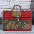 Decorative jewelry box with floral patterns on a wooden surface and brick wall background