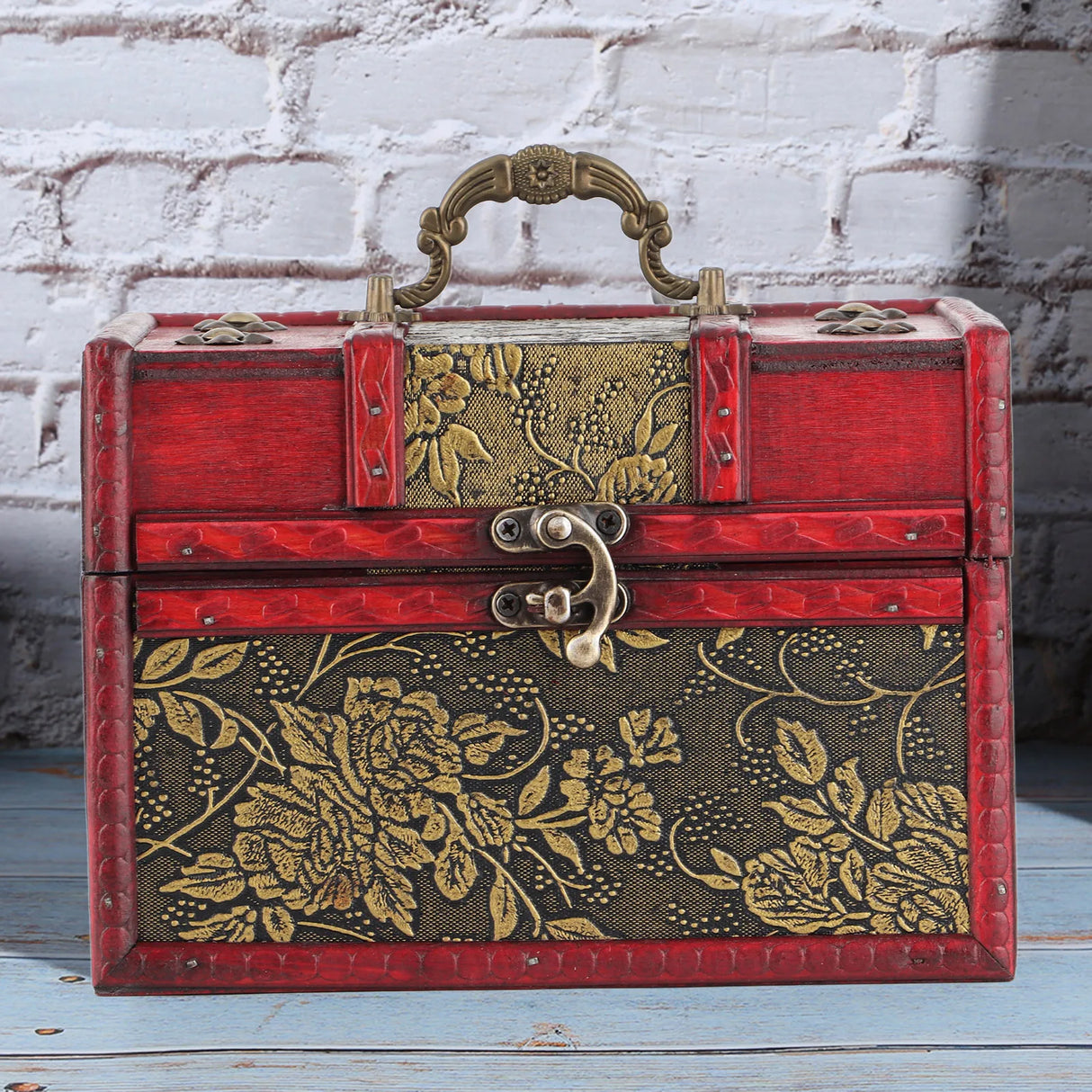 Decorative jewelry box with floral patterns on a wooden surface and brick wall background