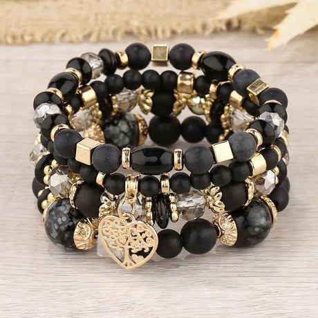 Stack of black and gold beaded bracelets on a light wooden surface