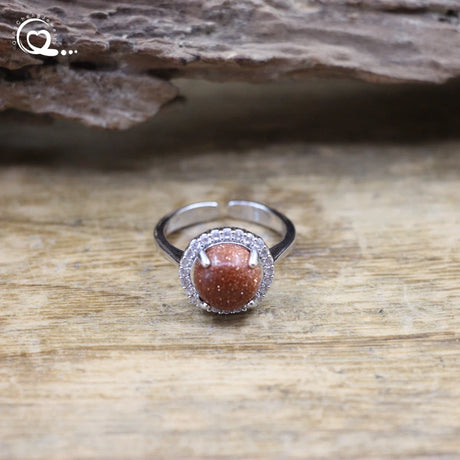 Silver ring with a brown gemstone on a wooden surface