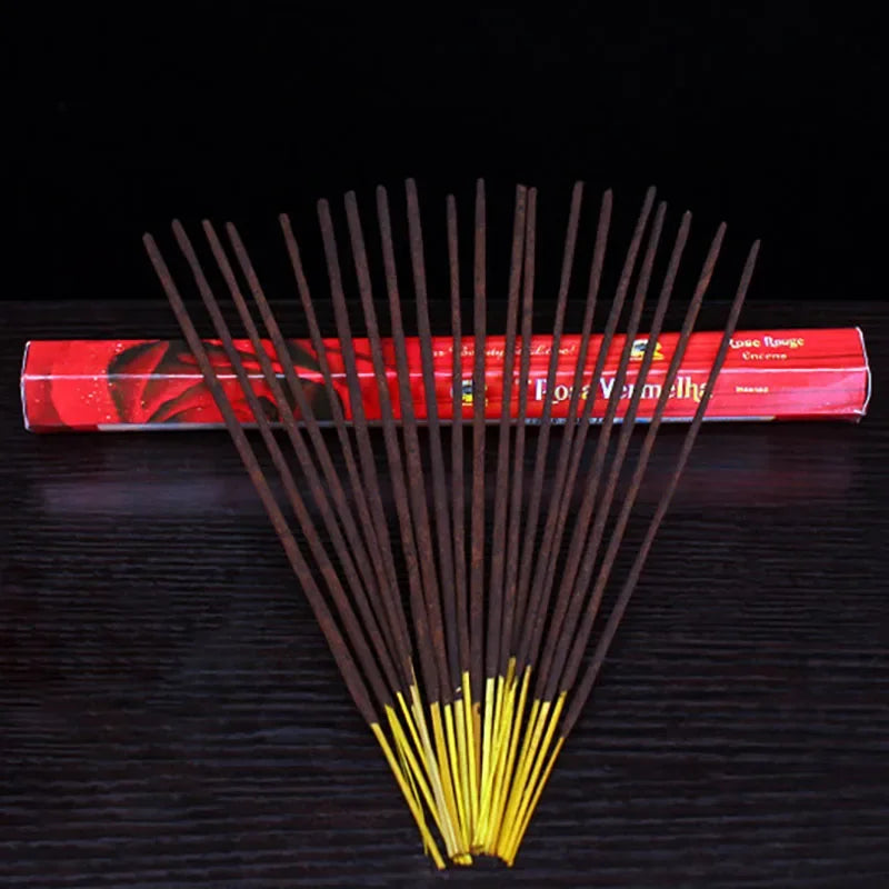 Incense sticks with a red cylindrical container on a dark surface