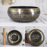 Tibetan singing bowl set with engraved designs on a textured surface.