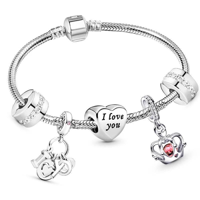 Silver bracelet with charms including a heart-shaped 'I love you' charm, a crown charm, and a heart charm with a red stone on a white background.