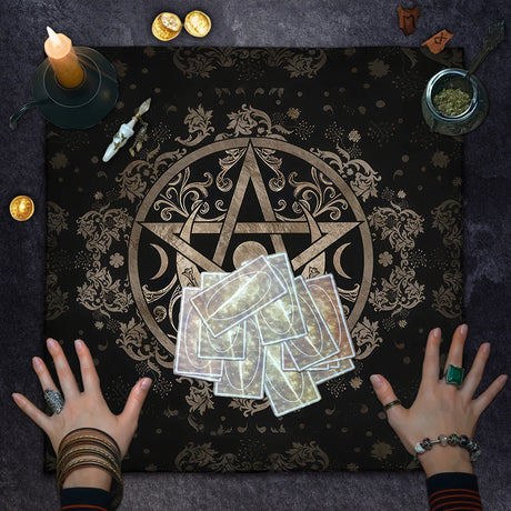 Tarot cards on a black cloth with a gold pentacle symbol, surrounded by candles and coins.