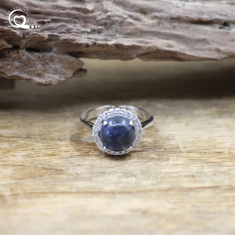 Silver ring with a blue gemstone on a wooden surface