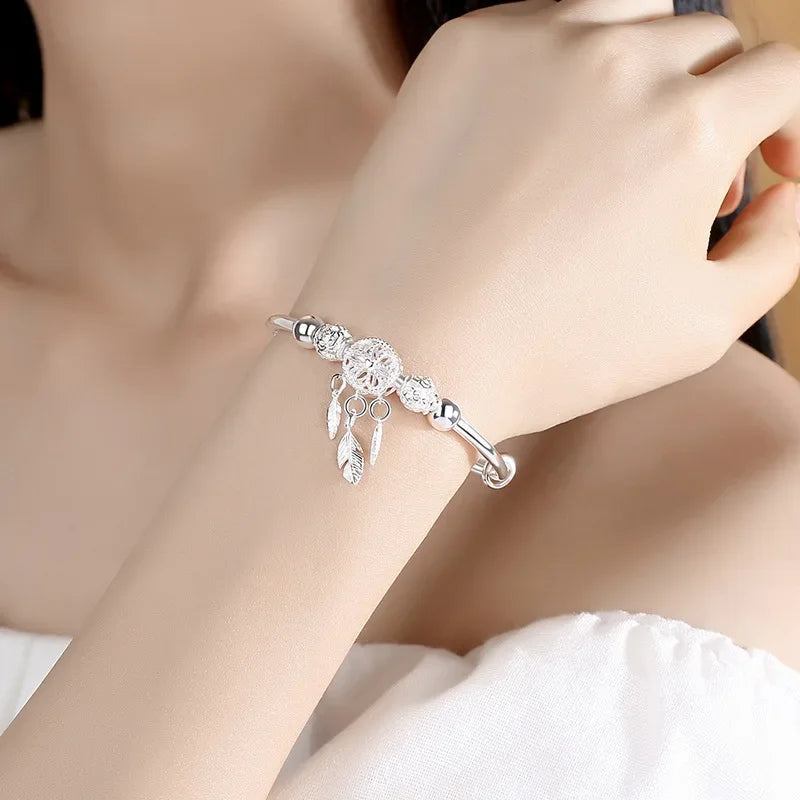 Silver bracelet with leaf and feather designs on a wrist