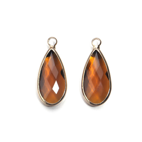 Teardrop-shaped amber stones with gold settings on a white background