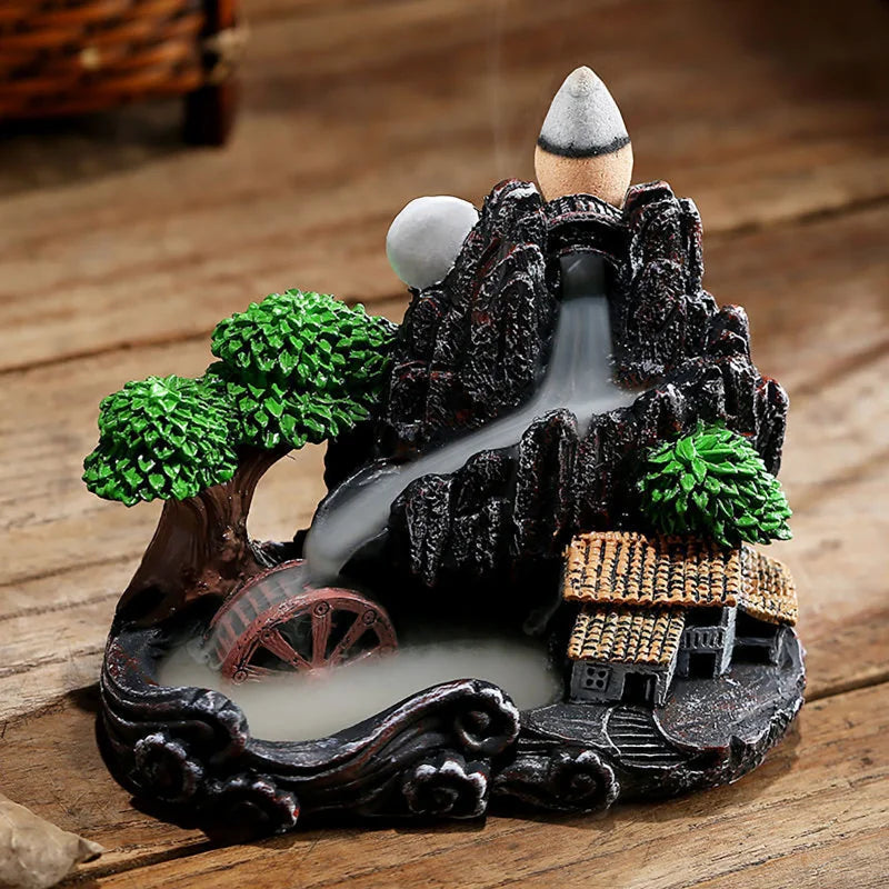 Decorative water fountain with trees, house, and wheel on a wooden surface