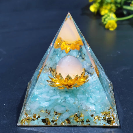 Pyramid-shaped crystal with gold elements and a light blue base on a dark surface.