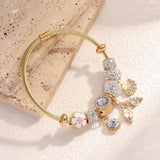 Gold bracelet with various charms on a textured beige surface