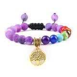 Multicolored beaded bracelet with a gold tree of life charm on a white background