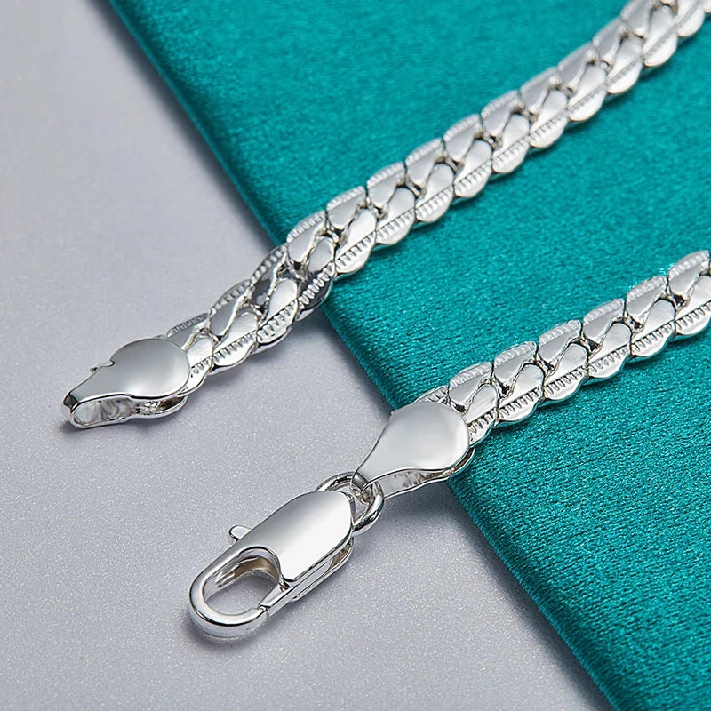 Silver chain bracelet with clasp on a teal fabric background