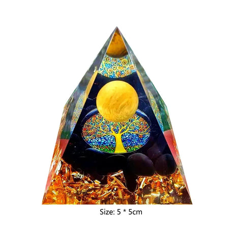 Triangular crystal orgone pyramid with tree of life design and yellow sphere on a white background