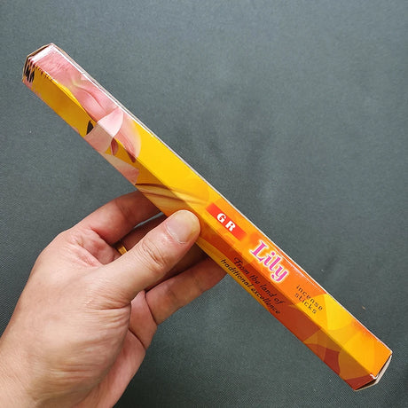 Hand holding a colorful product packaging with text on a gray background