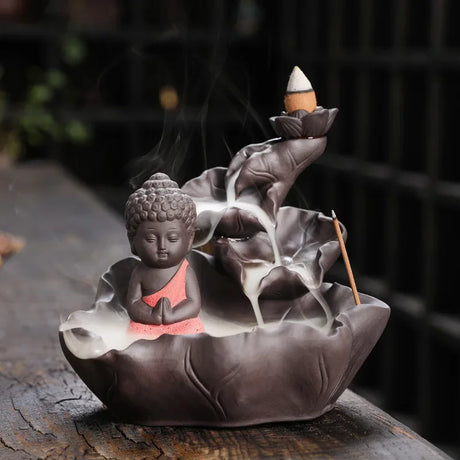 Incense burner with Buddha statue and incense sticks on a dark background