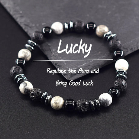 Black and white beaded bracelet on a dark surface with text about regulating the aura and bringing good luck.