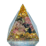 Pyramid-shaped crystal with embedded colorful stones on a white background