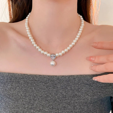 Pearl necklace with a heart-shaped clasp worn by a person
