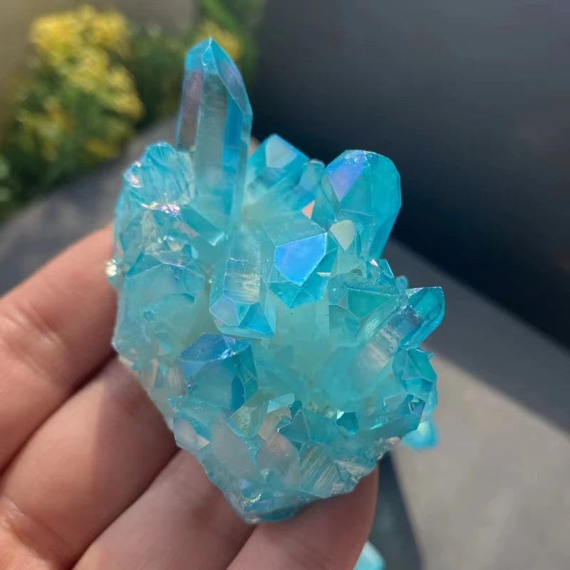 Blue crystal cluster held in a hand with a blurred background