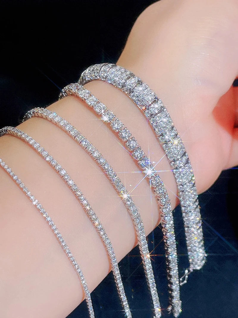 Close-up of a hand wearing multiple diamond bracelets on a dark background