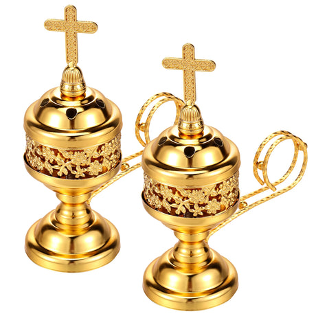 Two gold incense burners with cross tops on a white background
