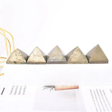 Five pyramid-shaped concrete blocks on a white surface with a pen and paper in the background.