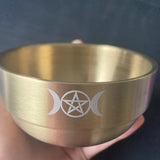 Gold cup with engraved symbol held by a hand against a dark background