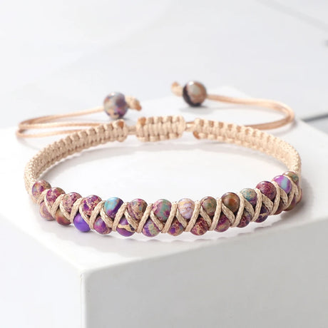 Beaded bracelet with purple and green stones on a white surface