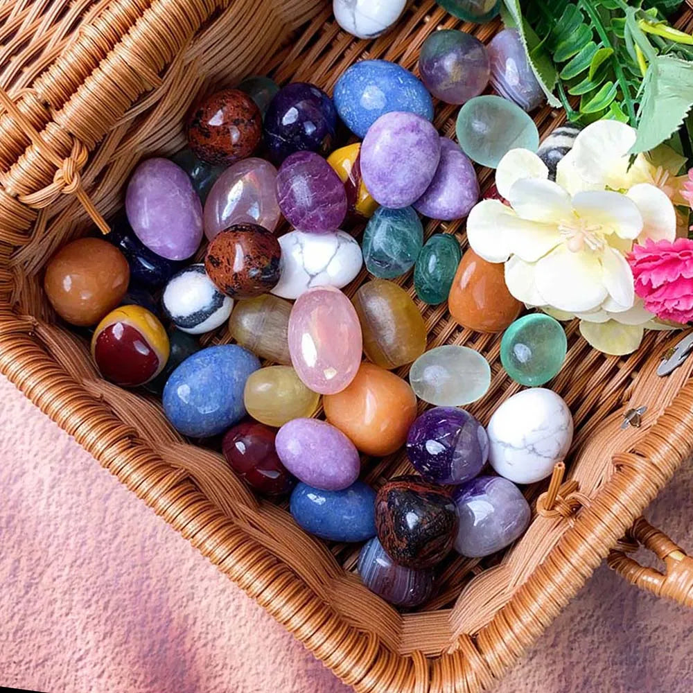 Basket filled with multicolored stones and flowers on a pink fabric background