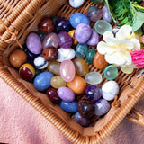 Basket filled with multicolored stones and flowers on a pink fabric background