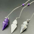 Three crystal pendants on silver chains against a gray background