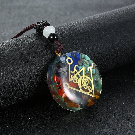 Round multicolored pendant with a gold symbol on a dark surface