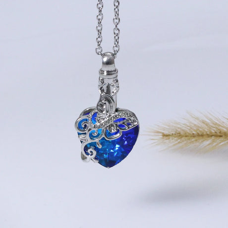Heart-shaped blue pendant on a silver chain against a light gray background