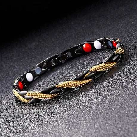 Bracelet with black, gold, red, and white beads on a dark surface