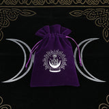 Purple drawstring bag with a white symbol on a black background with silver crescent moons.