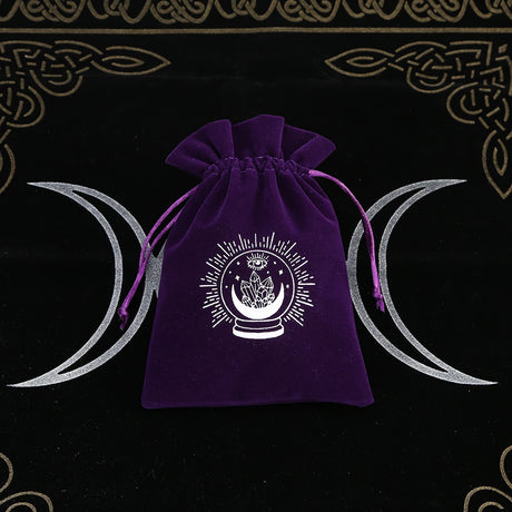Purple drawstring bag with a white symbol on a black background with silver crescent moons.
