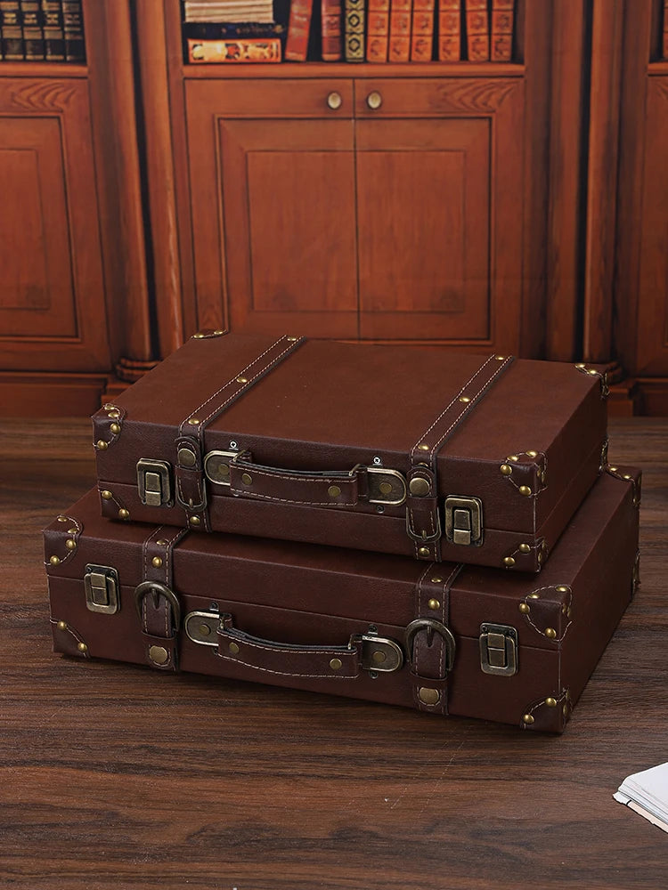 Two brown leather suitcases stacked on a wooden surface with a wooden cabinet in the background.