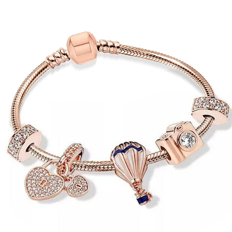 Rose gold bracelet with various charms on a white background