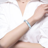 Person wearing a blue and silver bracelet on a white background