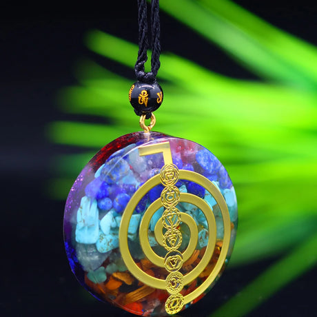 Colorful pendant with gold design on a black cord against a blurred green background