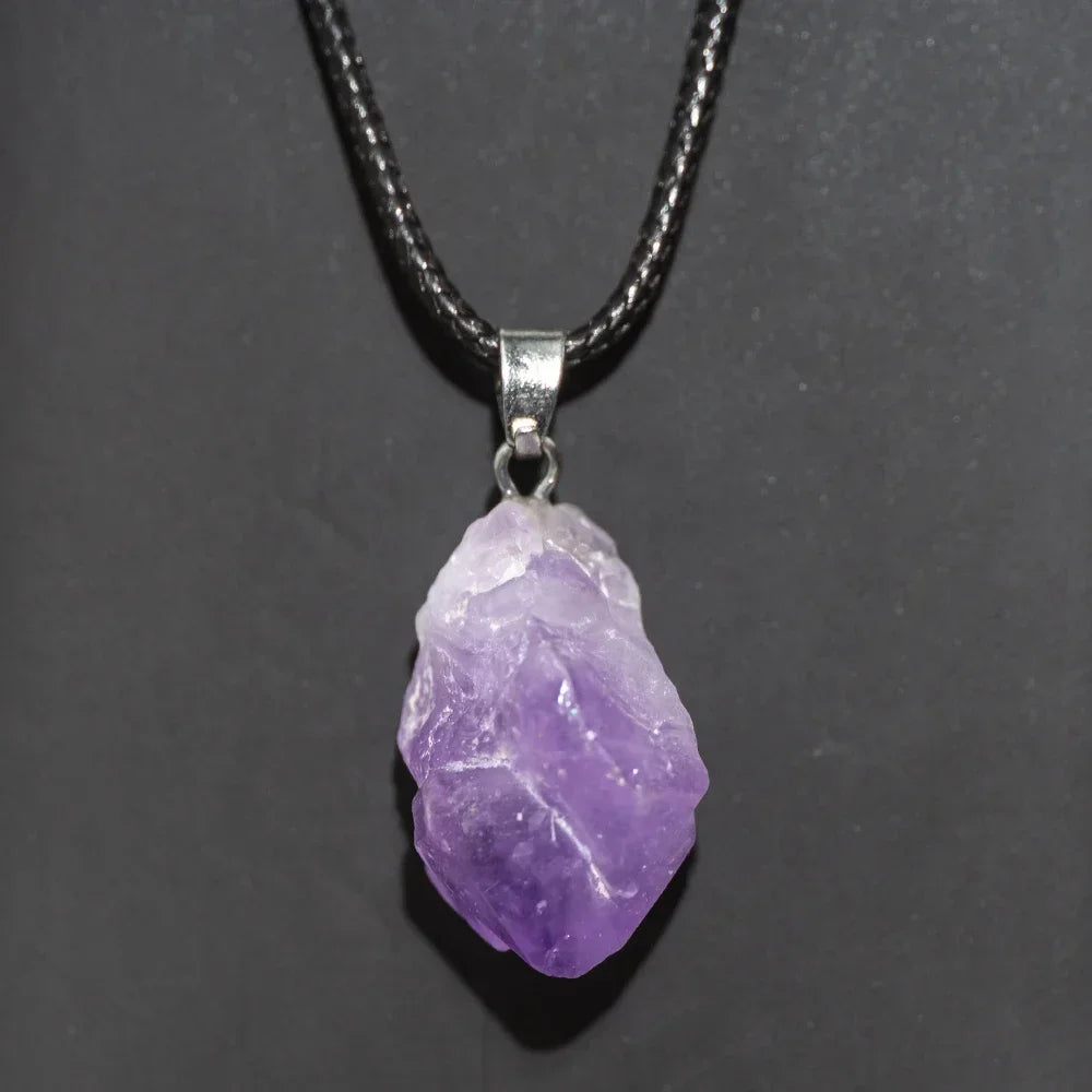 Purple crystal pendant on a black cord against a dark background
