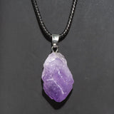 Purple crystal pendant on a black cord against a dark background