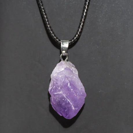 Purple crystal pendant on a black cord against a dark background
