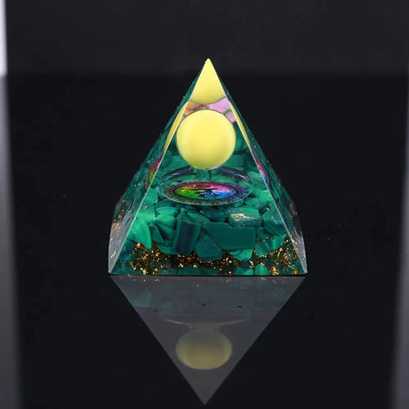 Pyramid-shaped decorative item with green base, colorful center, and yellow top on a black background