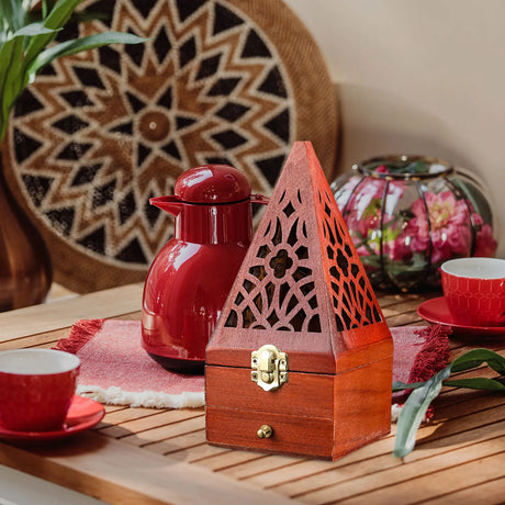 Red teapot and cups with a wooden decorative box on a wooden table.