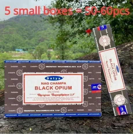 Box of Satya Nag Champa Black Opium incense with a single stick displayed outdoors.