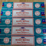 Multiple boxes of Satya Nag Champa Money Matrix incense on a wooden surface